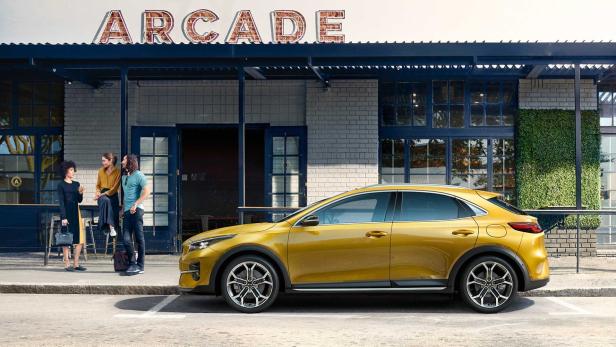 Ein goldfarbener Kia XCeed parkt vor einem Gebäude mit der Aufschrift „Arcade“.
