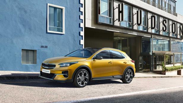 Ein goldfarbener Kia XCeed steht vor einem Gebäude mit der Aufschrift „Hudson“.