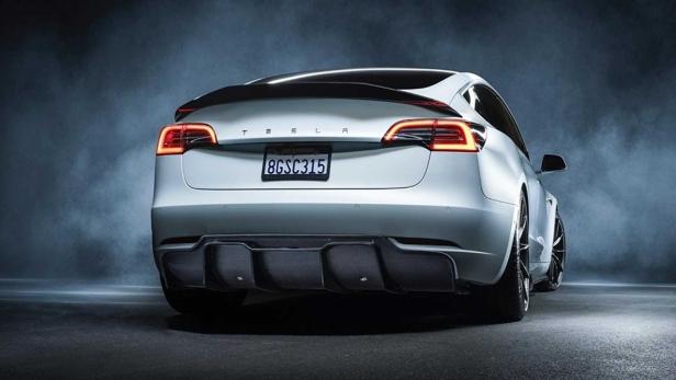 Die Rückansicht eines silbernen Tesla Model 3 mit einem Heckspoiler und einem kalifornischen Nummernschild.