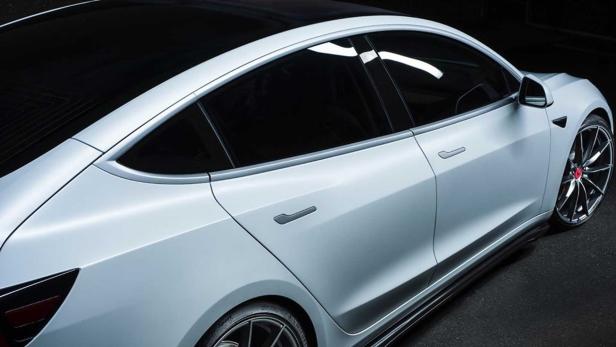 Die Rückansicht eines weißen Tesla Model 3 mit getönten Scheiben.