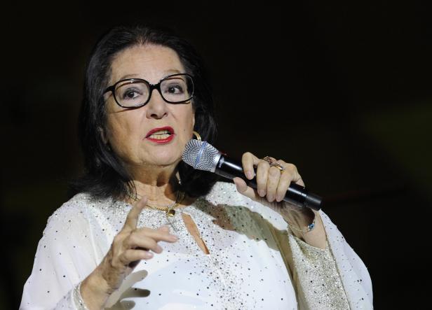 Eine Frau mit Brille singt in ein Mikrofon.