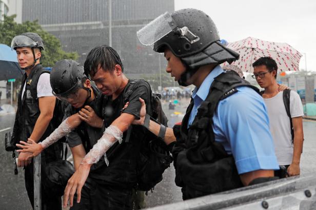 A protester who was pepper sprayed is detained during the anniversary