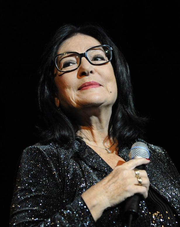 Eine Frau mit Brille hält ein Mikrofon und singt.