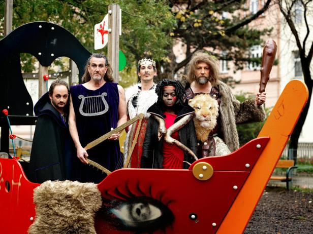 Eine Gruppe von als historische Figuren verkleideten Menschen posiert auf einem Spielplatz.