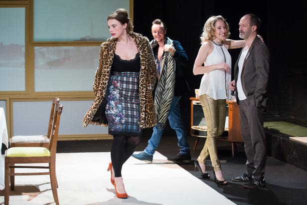 Vier Schauspieler stehen auf einer Bühne während einer Theatervorstellung.