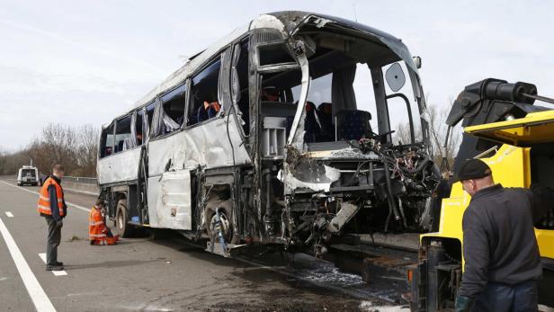 Ein schwer beschädigter Reisebus steht auf einer Autobahn und wird abgeschleppt.