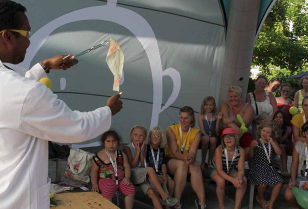 Ein Mann im Laborkittel zündet vor einer Gruppe von Kindern ein Tuch an.