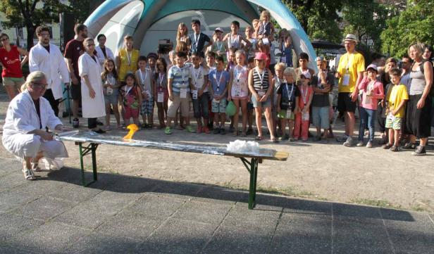 Eine Wissenschaftlerin führt vor einer Gruppe von Kindern ein Experiment mit Feuer durch.