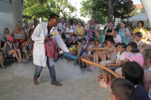 Ein Mann im Laborkittel führt ein Experiment mit Trockeneis vor einer Gruppe von Kindern durch.