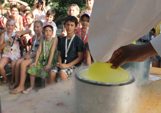 Eine Gruppe Kinder beobachtet eine Demonstration mit einem gelben Ballon und Trockeneis.