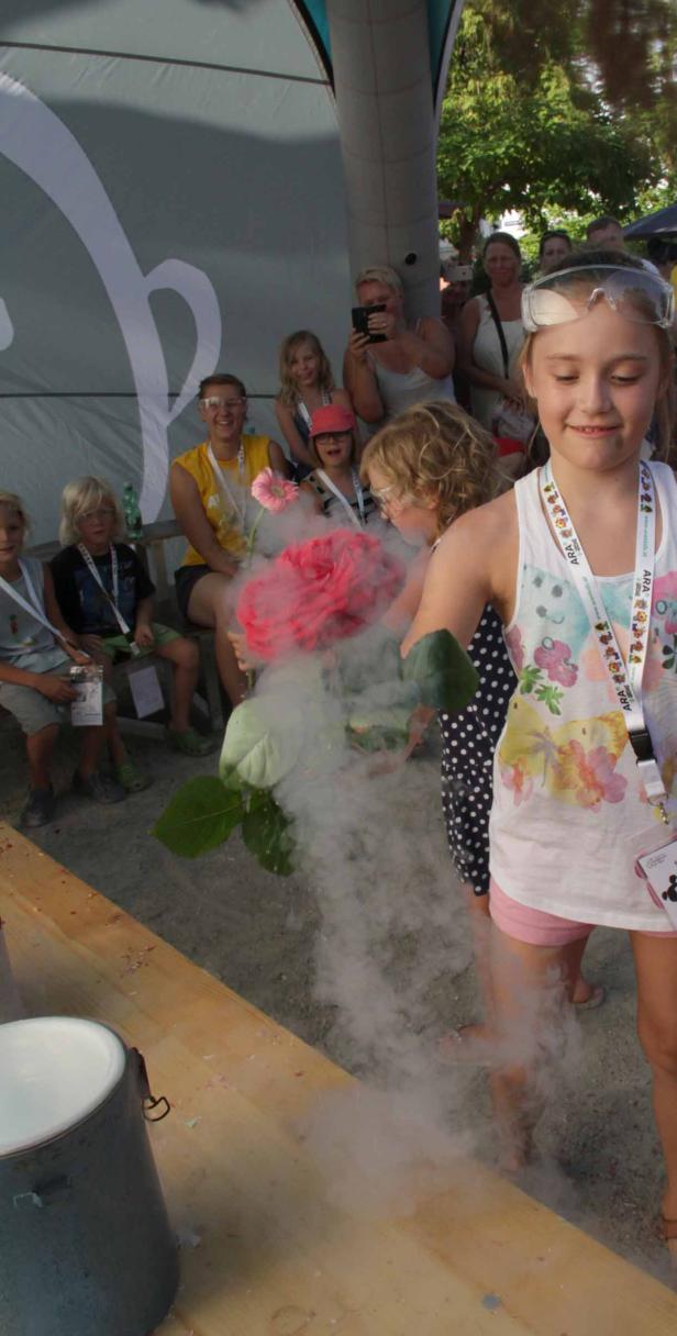 Ein Mädchen mit Schutzbrille hält eine rauchende, rote Rose in der Hand.