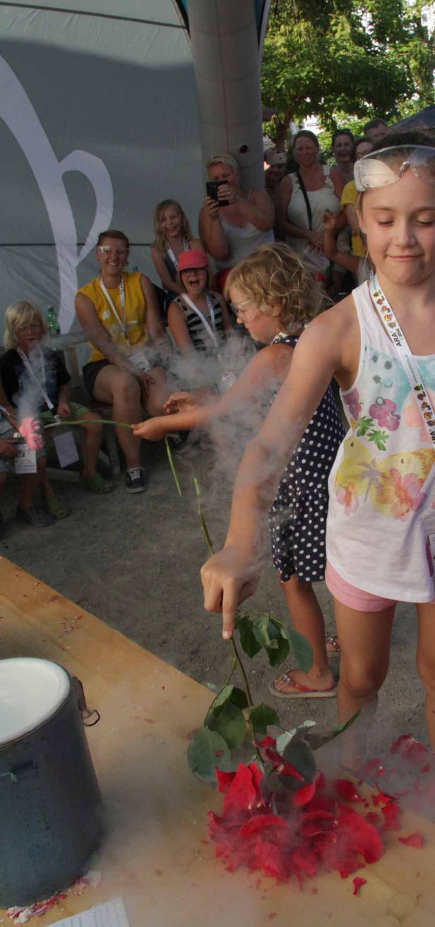 Mädchen experimentieren mit flüssigem Stickstoff und Rosen auf einer Veranstaltung.