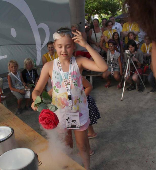 Ein Mädchen mit Schutzbrille hält eine rote Rose, aus der Dampf aufsteigt.