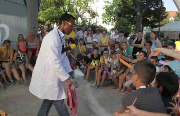 Ein Mann im Laborkittel führt ein Experiment mit Trockeneis vor einer Gruppe von Kindern durch.