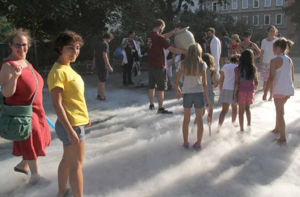 Eine Gruppe von Menschen steht in einer Nebelwolke im Freien.