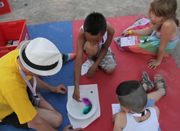 Kinder und ein Erwachsener experimentieren mit Farben in einer Schüssel.