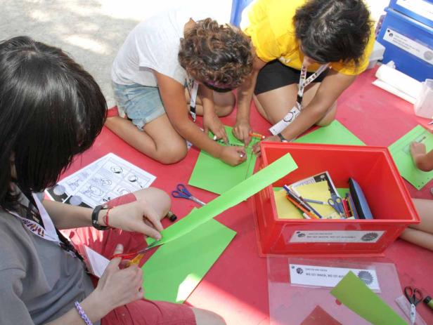 Kinder sitzen auf dem Boden und basteln mit Papier und Scheren.