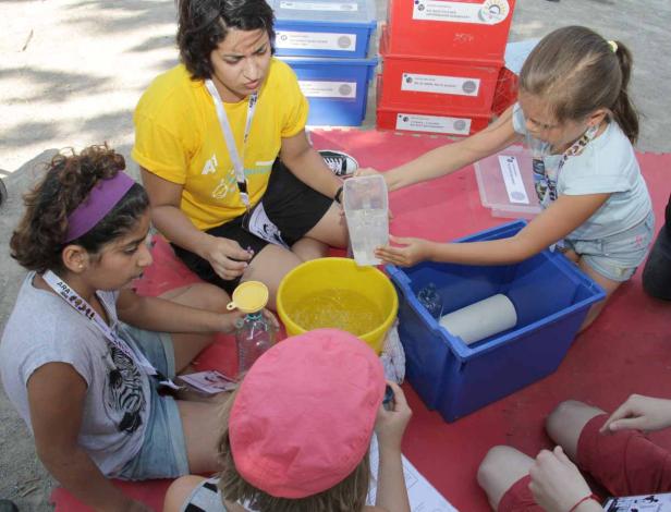 Eine Gruppe von Kindern experimentiert mit Wasser und Behältern im Freien.