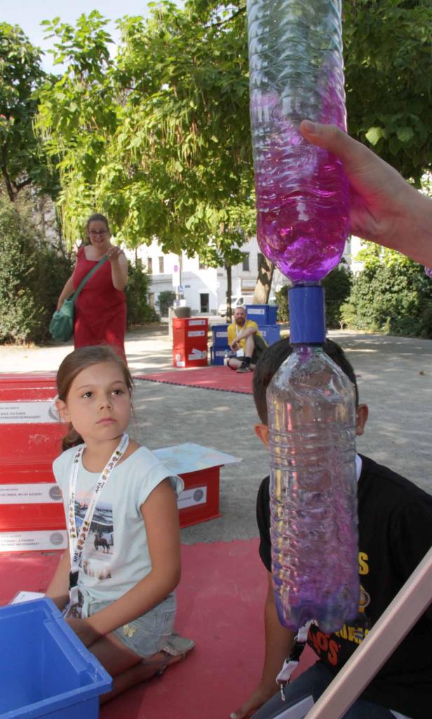 Kinder beobachten, wie Wasser von einer Flasche in eine andere fließt.