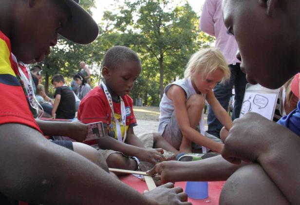 Eine Gruppe Kinder bastelt gemeinsam im Freien.
