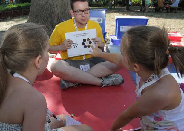 Ein Mann erklärt zwei Kindern eine optische Täuschung mit Kreisen.