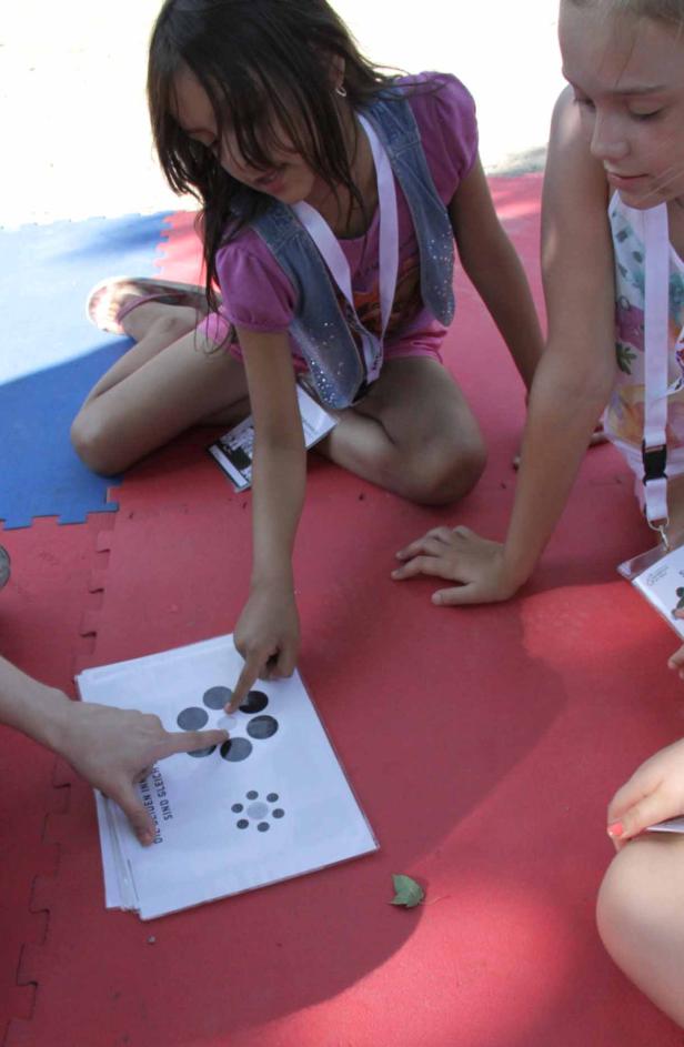 Zwei Mädchen sitzen auf dem Boden und spielen mit einem Spiel mit Punktmustern.
