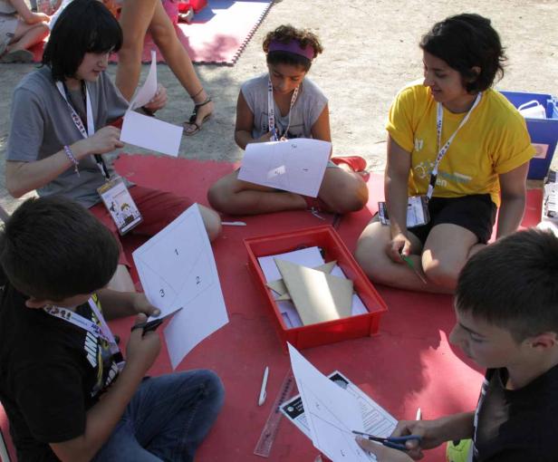 Eine Gruppe von Kindern sitzt auf dem Boden und schneidet Papier mit Scheren.
