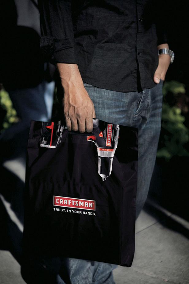 Ein Mann trägt eine schwarze Tasche der Marke Craftsman mit einem Akkuschrauber darin.