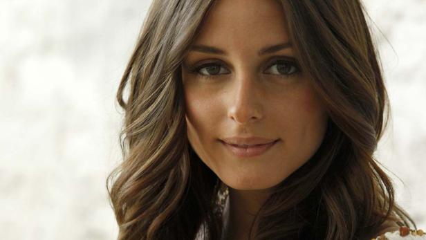 Ein Porträt von Olivia Palermo mit gewelltem, braunem Haar.