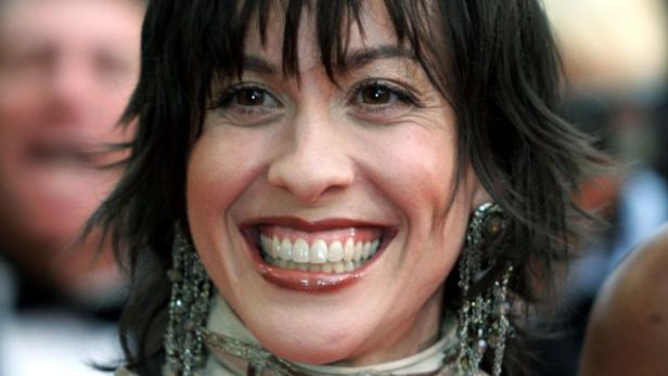 Nahaufnahme des lächelnden Gesichts von Alanis Morissette mit Ohrringen.