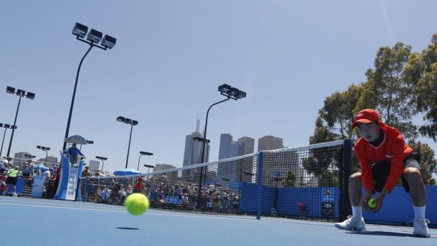 Ein Tennisspieler bereitet sich auf einem blauen Platz auf den Aufschlag vor.