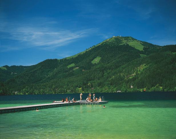 Menschen entspannen sich an einem sonnigen Tag auf einem Steg im See.
