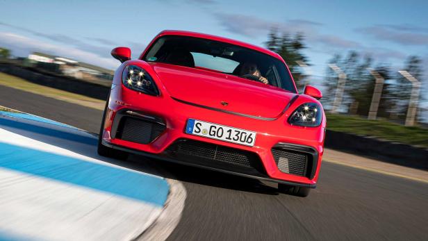Ein roter Porsche fährt auf einer Rennstrecke in eine Kurve.