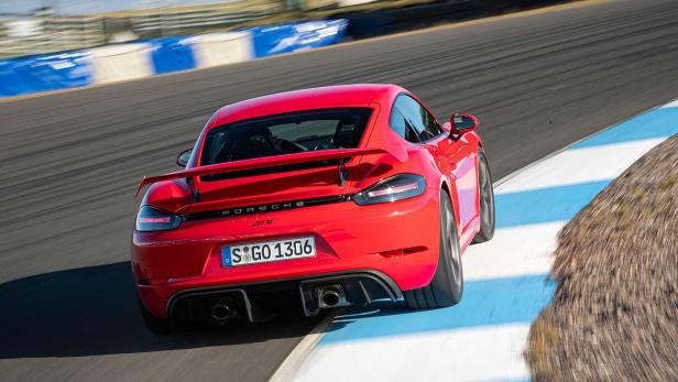 Ein roter Porsche 718 Cayman GT4 rast auf einer Rennstrecke.