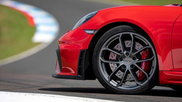 Detailansicht eines roten Porsche GT4 auf einer Rennstrecke.