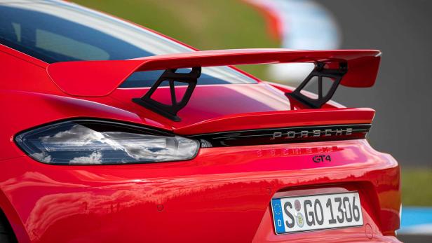Detailansicht des Hecks eines roten Porsche 718 Cayman GT4 mit Heckflügel.