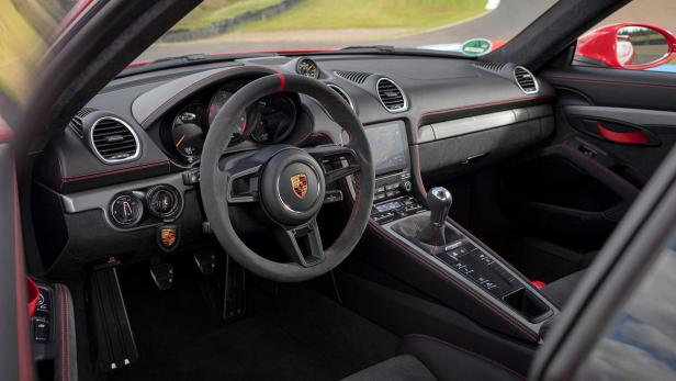 Innenansicht eines Porsche-Sportwagens mit schwarzem Interieur und roten Ziernähten.