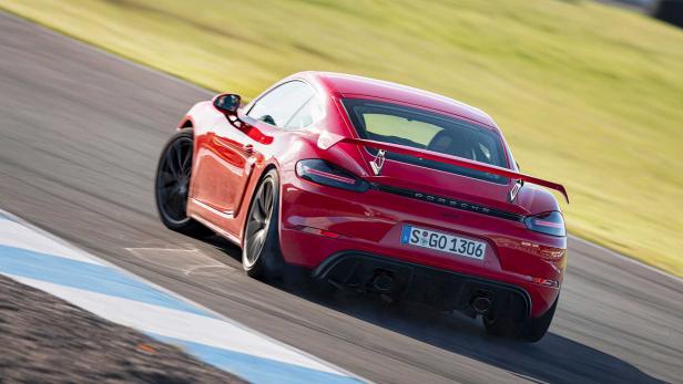 Ein roter Porsche 718 Cayman GT4 rast auf einer Rennstrecke.