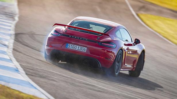 Ein roter Porsche 718 Cayman GT4 driftet auf einer Rennstrecke.