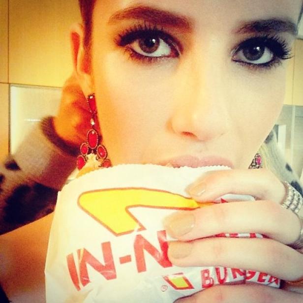 Eine Frau mit Ohrringen isst einen Burger von In-N-Out Burger.