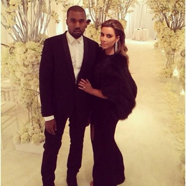 Kanye West und Kim Kardashian posieren vor einem Hintergrund aus weißen Blumen.