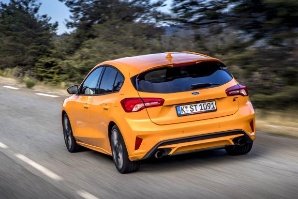 Ein orangefarbener Ford Focus ST fährt auf einer Landstraße.
