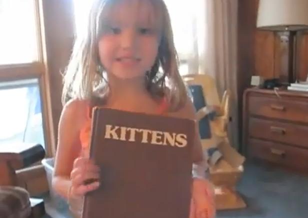 Ein Mädchen hält ein Buch mit dem Titel „Kittens“ in den Händen.