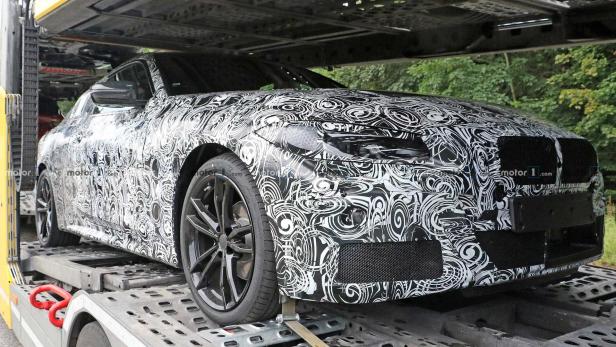 Ein Prototyp eines Autos mit einer schwarz-weißen Tarnung steht auf einem Anhänger.