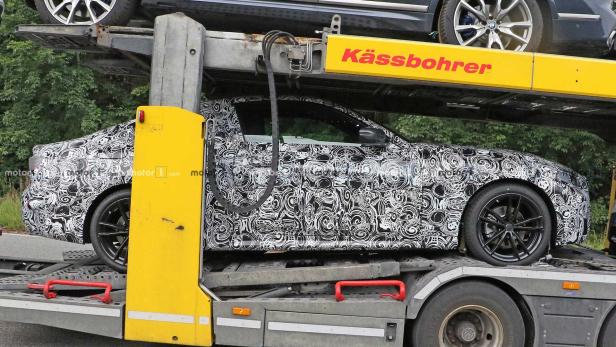 Ein mit einem Muster getarntes Auto auf einem Anhänger der Marke Kässbohrer.