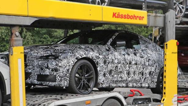 Ein mit Tarnmuster folierter BMW auf einem Autotransporter der Marke Kässbohrer.