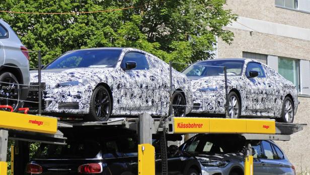 Mehrere BMW-Prototypen auf einem Autotransporter mit auffälliger Tarnung.