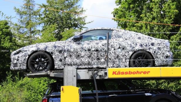 Ein mit Tarnmuster beklebter BMW steht auf einem Anhänger.