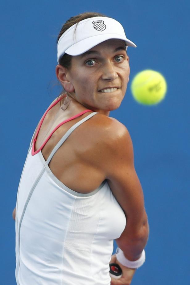 Eine Tennisspielerin schlägt einen gelben Tennisball.