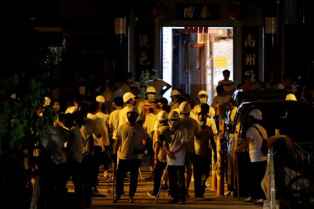 Men in white T-shirts and carrying poles are seen in Yuen Long after attacking anti-extradition bill demonstrators at a train station in Hong Kong